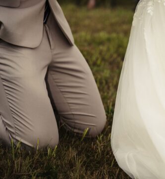 a bride and groom holding hands in the grass